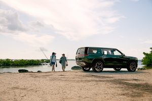 Two people alongside a lake with their Rivian R1S SUV
